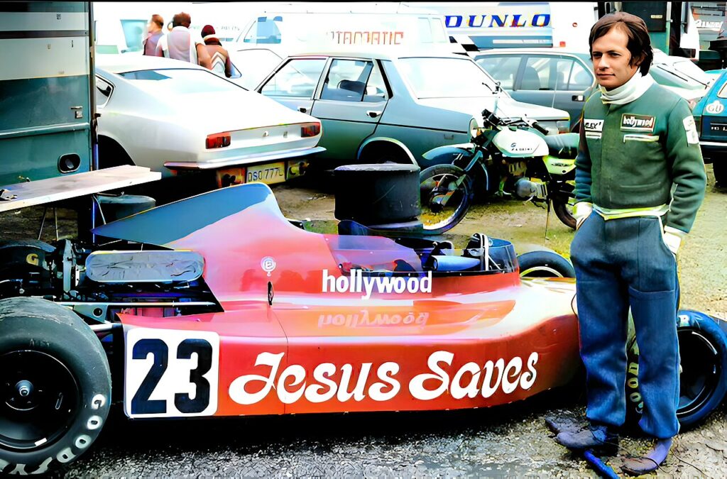 Alex Ribeiro aktywnie promował duchowe życie kierowcy F1. Chrześcijański slogan towarzyszył mu przez całą karierę motorsportową. Mężczyzna w zielonym kombinezonie stoi obok czerwonego bolidu z numerem 23 i dużym napisem "Jesus Saves" oraz "hollywood".