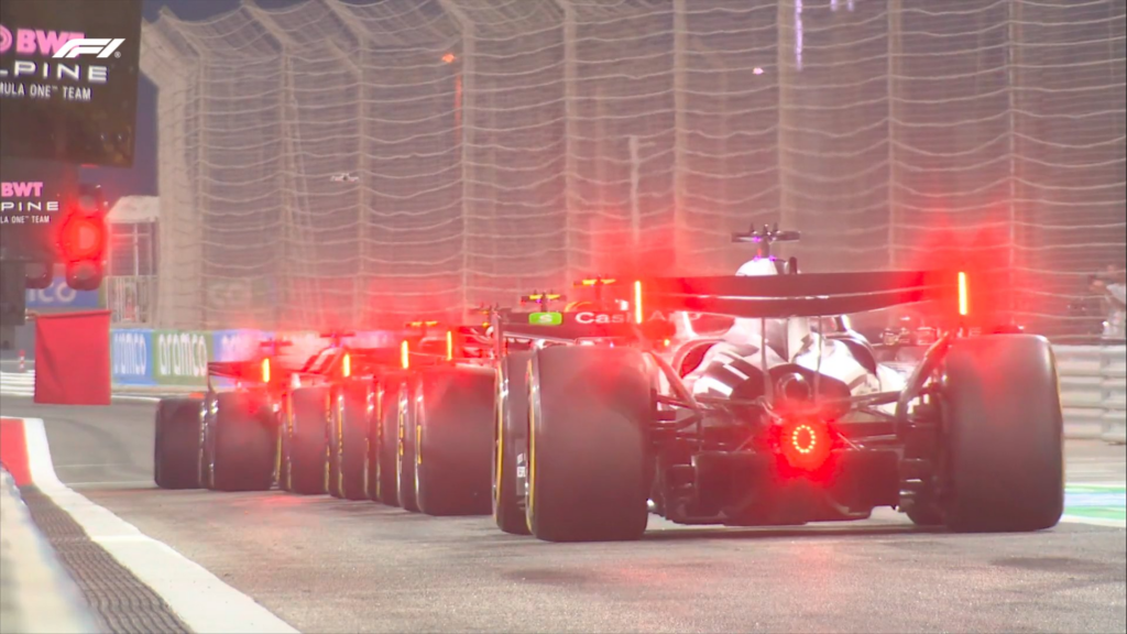 Testy F1 – kierowcy w oczekiwaniu na zieloną flagę w alei serwsiowej.
