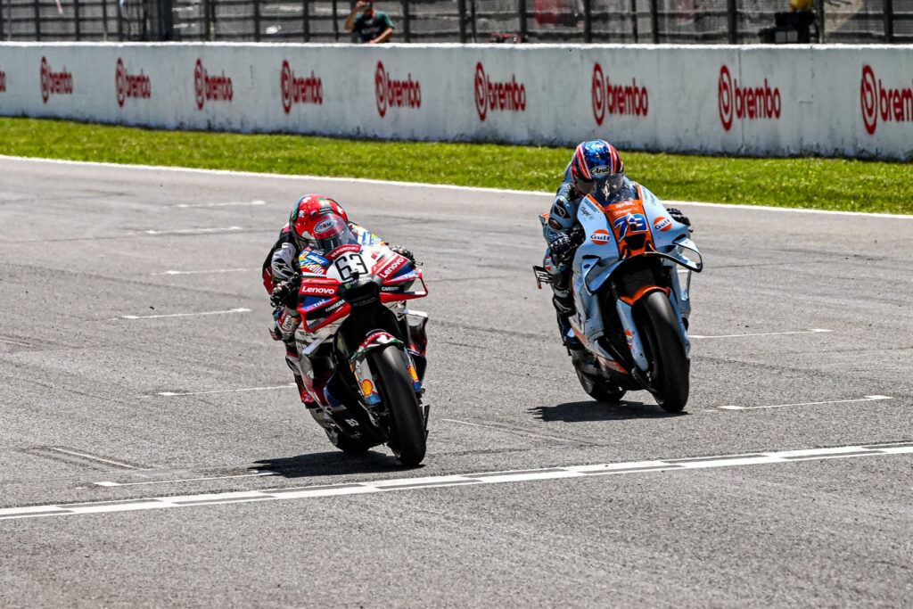 Francesco Bagnaia (#63) zdobywający podium przed Aiem Ogurą (#79) w Grand Prix Włoch